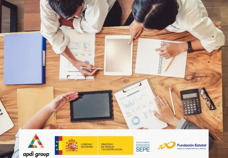 Mesa con una tablet y las manos de tres personas que manejan documentos