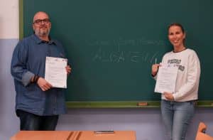 El CEO de APDI Group, Juan Antonio Rosado, y la directora del colegio público Gómez Moreno de Granada, Sara Arteaga, firman la donación de libros a la biblioteca del centro